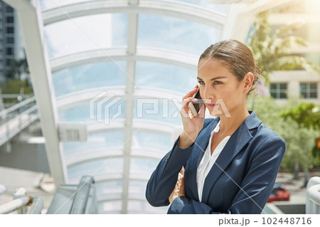 Im listening. a young businesswoman talking on her cellphone while standing at the top of an escalator. Im listening. a young businesswoman talking on her cellphone while standing at the top of an escalator. 102448716