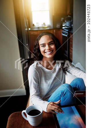 Shopping from the comfort of home. a young woman drinking coffee and shopping online with her digital tablet at home. Shopping from the comfort of home. a young woman drinking coffee and shopping online with her digital tablet at home. 102448723