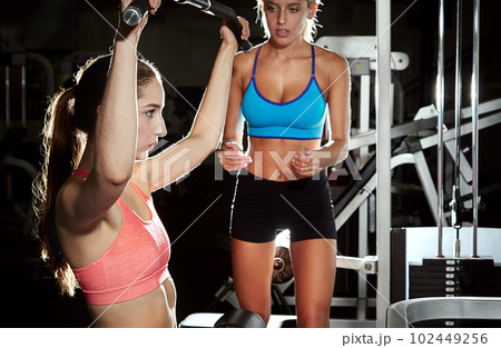 You can do this. a young woman working out at the gym with her friend encouraging her. 102449256