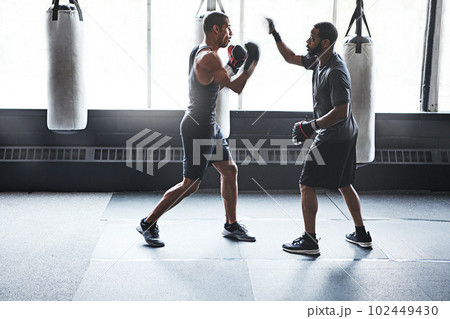 Everyone you meet has something to teach. a male boxer practising his moves with his coach. 102449430