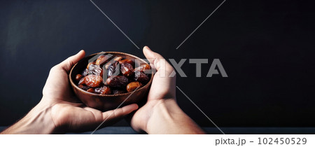 A Muslim man holds out bowl of dates. Traditional distribution of food charity for the events Ramadan Kareem, Mubarak, Eid-al-adha 102450529