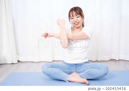在宅勤務時ストレス解消のためにヨガマットを敷いてストレッチをする30代女性 在宅勤務時ストレス解消のためにヨガマットを敷いてストレッチをする30代女性 102453418