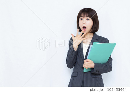 白い背景の前でびっくりしている30代のスーツ姿の女性 白い背景の前でびっくりしている30代のスーツ姿の女性 102453464