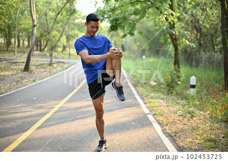 Handsome Asian man in sportswear stretching his leg on a street before running. 102453725