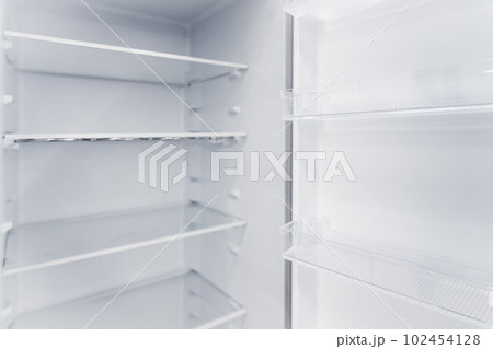 Empty white vertical new home refrigerator with shelves 102454128