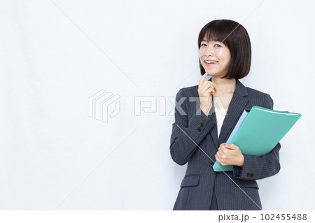 白い背景の前で笑顔で考えているスーツ姿の30代女性 102455488