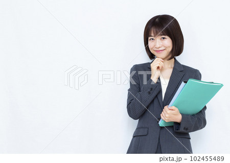 白い背景の前で笑顔で考えているスーツ姿の30代女性 102455489