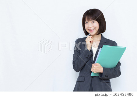 白い背景の前で笑顔で考えているスーツ姿の30代女性 102455490