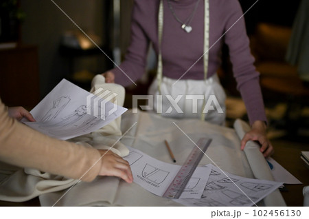 Two female fashion designers are discussing and working together in a studio. 102456130