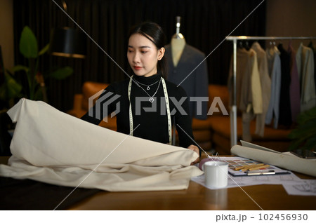 Beautiful female fashion designer checking the quality of the fabric in her studio. Beautiful female fashion designer checking the quality of the fabric in her studio. 102456930