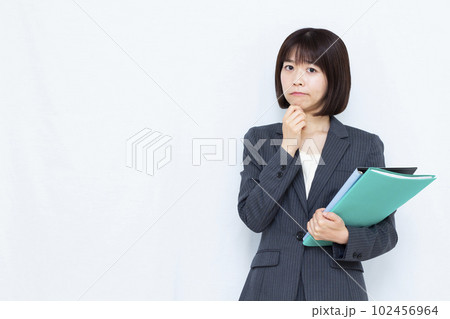 白い背景の前で悩んでいるスーツ姿の30代女性 102456964