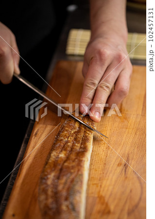 Chef slicing eel for japanese sushi rolls cooking Chef slicing eel for japanese sushi rolls cooking 102457131