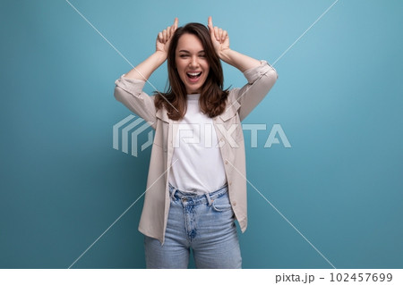 well-groomed brunette young woman in a stylish image posing on a blue background with copy space 102457699