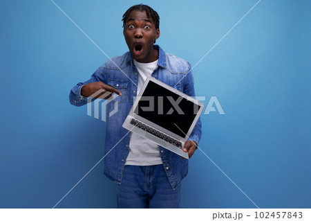 energetic american man with dreadlocks in denim jacket showing laptop screen with mockup energetic american man with dreadlocks in denim jacket showing laptop screen with mockup 102457843