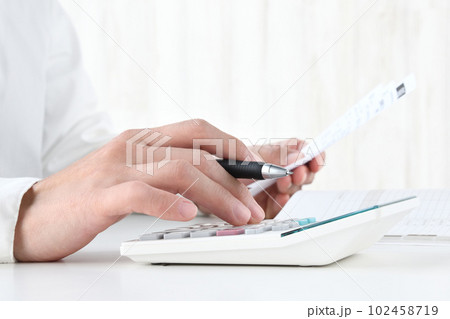 レシートを片手に計算機を使う人物の手元 102458719