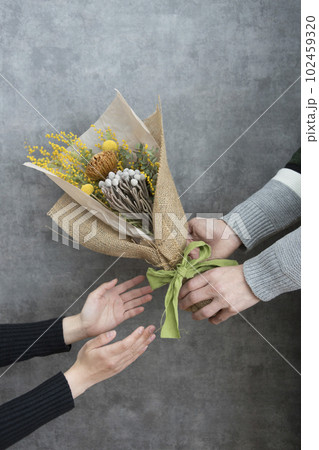 ドライフラワーの花束を手渡す男女 102459320