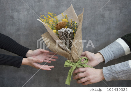 ドライフラワーの花束を手渡す男女 102459322