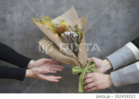ドライフラワーの花束を手渡す男女 ドライフラワーの花束を手渡す男女 102459323