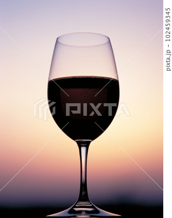 赤ワインの入ったワイングラスと夕景のグラデーション 赤ワインの入ったワイングラスと夕景のグラデーション 102459345