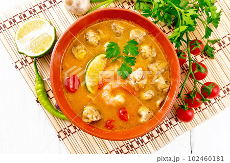 Soup Tom Yum with lime in bowl on light board top Soup Tom Yum with lime in bowl on light board top 102460181