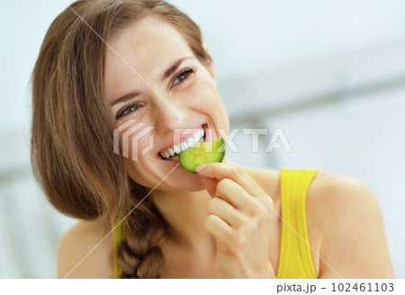 young woman eating cucumber in kitchen 102461103