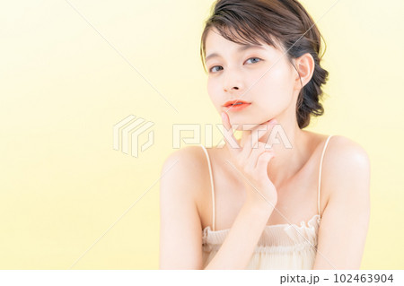 イエローバックでスキンケアをする若い女性 イエローバックでスキンケアをする若い女性 102463904