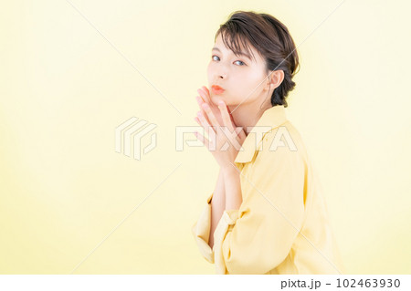 おしゃれな服でイエローバックでポーズを取る若い女性 102463930