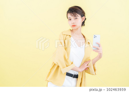イエローバックでスマホを操作する若い女性 イエローバックでスマホを操作する若い女性 102463939