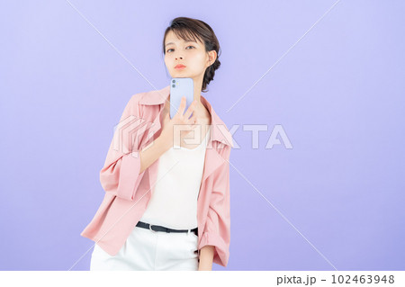 パープルバックでジャケットを着てスマホを操作する若い女性 パープルバックでジャケットを着てスマホを操作する若い女性 102463948