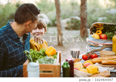 Father hugs his school boy son on a family picnic in mountains forest park. Child kid and his dad taking a rest and enjoying a picnic while hiking in the mountains Father hugs his school boy son on a family picnic in mountains forest park. Child kid and his dad taking a rest and enjoying a picnic while hiking in the mountains 102464497