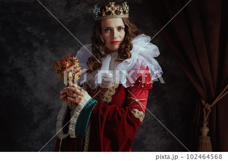 medieval queen in red dress with dried flower and white collar 102464568