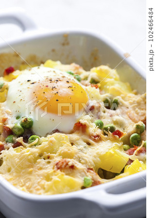 potatoes baked with smoked meat, green peas and cheddar cheese served with fired egg 102466484