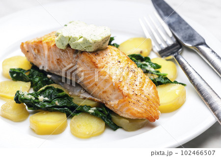 baked salmon with spinach leaves and potatoes 102466507