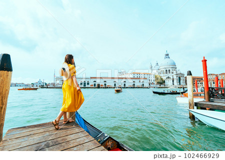 woman in yellow summer dress walking by Venice looking at grand canal 102466929
