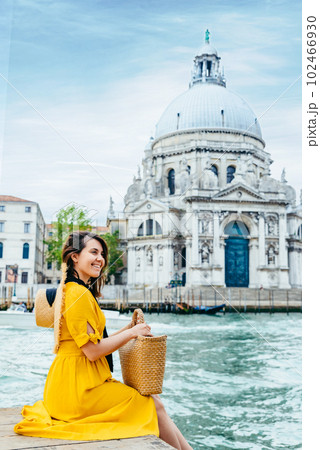 woman in yellow sundress sitting on pier with view of grand canal woman in yellow sundress sitting on pier with view of grand canal 102466930