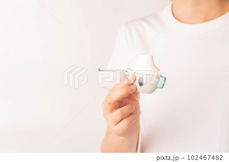 Young asian woman using Tiotropium bromide asthma inhaler over white background. Pharmaceutical products is used to treatment COPD and asthma. Close up. 102467482