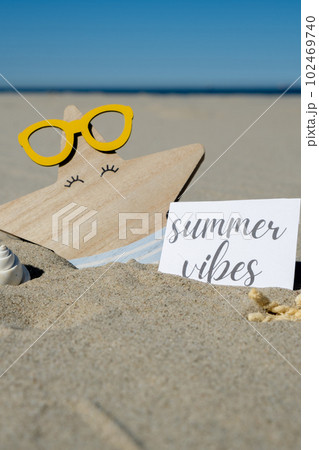 SUMMER VIBES text on paper greeting card on background of funny starfish in glasses summer vacation decor. Sandy beach sun coast. Holiday concept postcard. Getting away Travel SUMMER VIBES text on paper greeting card on background of funny starfish in glasses summer vacation decor. Sandy beach sun coast. Holiday concept postcard. Getting away Travel 102469740