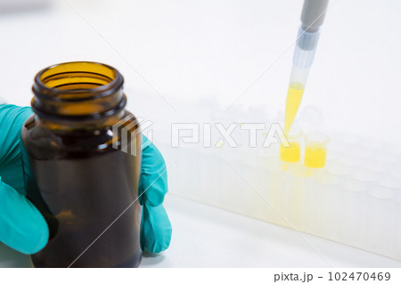 Laboratory worker pours liquid samples into glass tubes with pipette dispenser. Scientist does chemical test using glassware Laboratory worker pours liquid samples into glass tubes with pipette dispenser. Scientist does chemical test using glassware 102470469