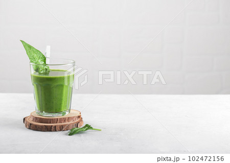 Healthy green smoothie with spinach, banana, and vegan milk in glass on light grey background, copy space 102472156