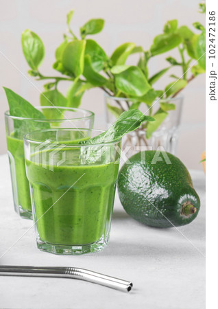Healthy green smoothie with spinach, avocado, banana, and vegan milk in two glasses and fresh ingredients on gray table Healthy green smoothie with spinach, avocado, banana, and vegan milk in two glasses and fresh ingredients on gray table 102472186