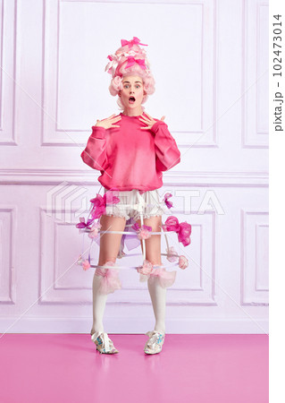 Portrait of beautiful woman, queen, princess wearing pink wig over luxury interior background. Royal person 102473014