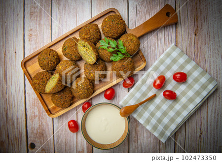 Falafel balls on a wooden cutting board and tahini sauce 102473350
