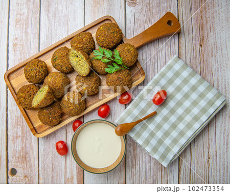 Falafel balls on a wooden cutting board and tahini sauce Falafel balls on a wooden cutting board and tahini sauce 102473354
