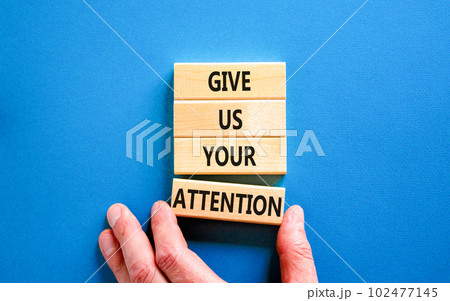Give us your attention symbol. Concept words Give us your attention on wooden block. Beautiful blue table blue background. Motivational business give us your attention concept. Copy space. 102477145