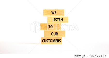 We listen to our customers symbol. Concept words We listen to our customers on wooden block. Beautiful white table white background. Business we listen to our customers concept. Copy space. 102477173