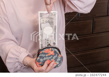 【がま口から10000円札を出す主婦】 102477244