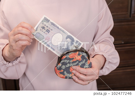 【がま口から1000円札を出す主婦】 【がま口から1000円札を出す主婦】 102477246