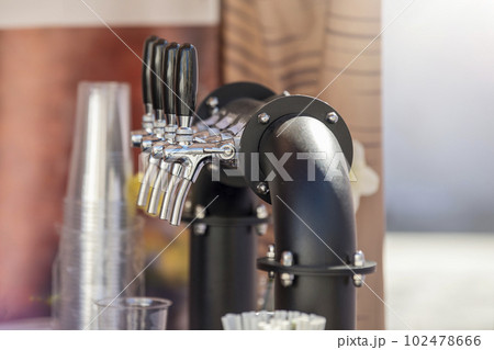 Handmade beer faucet. Bar counter in a pub with a beer tap, side view. The concept of buying, selling and drinking beer. Handmade beer faucet. Bar counter in a pub with a beer tap, side view. The concept of buying, selling and drinking beer. 102478666