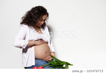Attractive dark haired curly multi ethnic pregnant woman, gravid mama, touching her belly, isolated on white background. Body positivity. Pregnancy. Maternity. Expecting baby. Femininity. Sensuality Attractive dark haired curly multi ethnic pregnant woman, gravid mama, touching her belly, isolated on white background. Body positivity. Pregnancy. Maternity. Expecting baby. Femininity. Sensuality 102478715