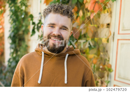 Close up shot of curly European male with beard wears switshot outdoors. Handsome man with crisp light hair. 102479720